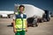 Laughing airport worker with truck on blurred background