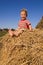 Laughing barefooted baby boy sit on a hayrick