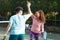 Laughing biracial couple playing tennis shaking hands on sunny outdoor tennis court