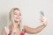 Laughing blonde woman making selfie on mobile phone against a g