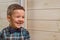 Laughing boy of 4 years old in a blue tart shirt on a light wooden background