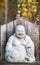 The Laughing Buddha, Budai, with his cloth sack stone sculpture with yellow fall colors in the background