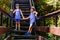 Laughing children in striped t-shirts and blue shorts stand holding hands on the steps in the summer