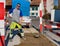 Laughing construction worker with broom standing on sand in front of vehicle and trailer looking into camera