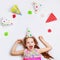 Laughing curly girl in carnival party hat, lying on a light back