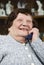 Laughing elderly woman calling by phone