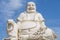 Laughing fat Buddha white statue with blue sky background