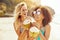 Laughing friends in bikinis drinking from coconuts on a beach