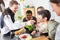 Laughing friends in the kitchen prepare and taste food