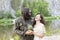 laughing girl in dress and brutal bearded man in army clothes walk along shore. Happy loving couple on romantic date