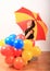 Laughing girl with red and yellow umbrella behind inflating balloons