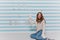 Laughing girl in white sweater plays in snowballs on winter photoshoot. Indoor portrait of curly woman in knitted hat