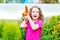 Laughing girl with yellow carrot in the garden.