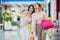 Laughing girls carrying bags with purchases in shopping mall