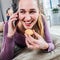 Laughing gorgeous young woman talking on smartphone, eating a cookie