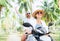 Laughing happy couple travelers riding motorbike during their tropical vacation under palm trees. Man emotionally raised hand up