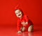 Laughing infant baby girl toddler in red bodysuit at Christmas New Year stands on all fours crawling