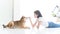 Laughing jocund young asian woman sitting on the floor playing with her Shiba Inu Japanese dog