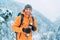 Laughing Man dressed bright orange softshell jacket with a hot drink thermos flask looking at camera while he trekking winter