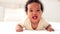 laughing portrait close-up of a small African-American baby girl in a white bodysuit on the bed at home, a funny six