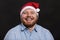 Laughing redhead man in a Santa hat. Close-up. Black background