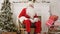 Laughing Santa sitting in a chair in his Christmas workshop