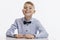 Laughing schoolboy in a blue shirt with a bow tie sits at the table. Back to school. White background