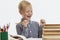 A laughing schoolboy sits at a table with textbooks and does homework. Back to school. White background