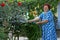 Laughing senior woman irrigating flower garden