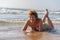 Laughing slender lady in a bathing suit lies and sunbathes on the sea shallow water