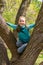 Laughing teenage girl climbed a tree in the park