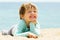 Laughing three-year girl laying on beach