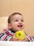 Laughing toddler holds an apple