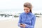 Laughing woman holding smart phone with earphones on beach