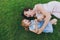 Laughing woman in light dress and little cute child baby girl lie on green grass lawn tickle, play and have fun. Mother