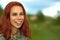 Laughing woman with short red hair posing on green field.