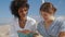 Laughing women reading book on beach closeup. Love partners enjoying summer