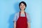 Laughing young asian male waiter with red apron