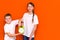 Laughing young caucasians two friends guy and girl in white empty blank design t-shirts posing on orange studio wall