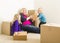 Laughing Young Family In Empty Room Playing With Moving Boxes