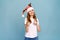 Laughing young santa girl in funny decorative deer horns on her head, pointing