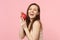 Laughing young woman in light clothes holding fresh ripe pitahaya, dragon fruit isolated on pink pastel wall background