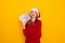 Laughing young woman Santa woman hold house, fan of cash money in dollar banknotes in Christmas hat posing isolated on red