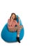 Laughing young woman sitting on blue beanbag chair and talking o