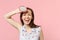 Laughing young woman in summer clothes holding half of fresh ripe pitahaya dragon fruit isolated on pink pastel