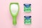 Laundry capsules and measuring scoop of washing powder on pink background, flat lay