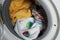 Laundry detergent capsules and clothes in washing machine drum, closeup view