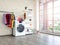 Laundry room interior with washing machine and colorful clothes on white vintage brick wall background