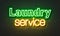 Laundry service neon sign on brick wall background.