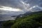 Lava coastline with a volcano under a dramatic sky at sunset on the island of Pico